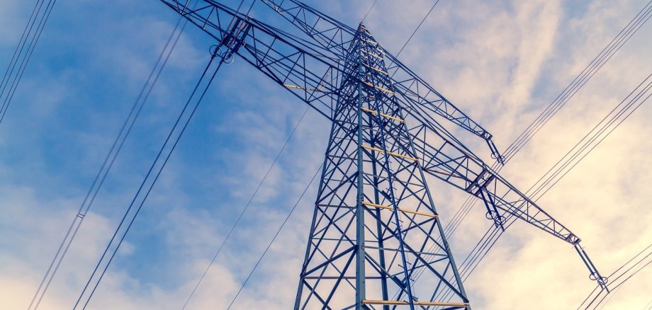 Strommast Hochspannungsleitung vor blauem Himmel